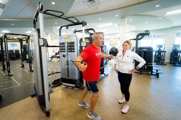 woman trainer with man working out in gym